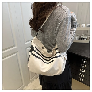 Détail du sac en toile crème avec rayures noires et poche latérale sur un grand sac cabas