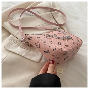 Close-up of pink bucket bag with bear print and golden chain on beige fabric background