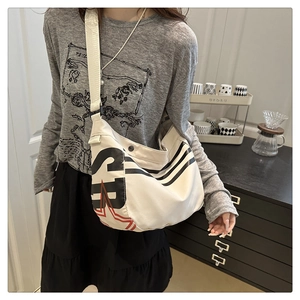 Détail d'un sac en toile blanc avec lettre S noire et motif graphique d'étoile rouge