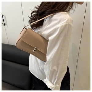 Milk tea colored faux leather underarm bag with gold metal buckle shown on a model
