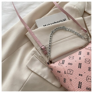 Detail of pink bucket bag with bear print, textured leather, and silver chain strap