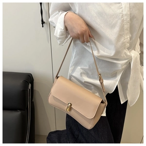 Detail of beige leather shoulder bag with gold metal buckle closure on female model