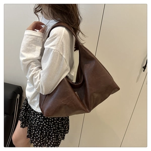 Detailed view of large brown shoulder bag in matte PU leather worn by a model