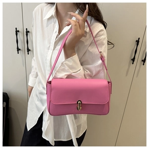 Close-up of pink matte leather shoulder bag with gold metal buckle and slim strap
