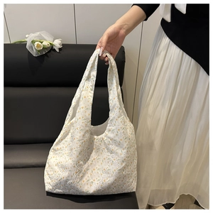 Close-up of floral embroidery and lace trim on a white canvas tote bag in a home setting