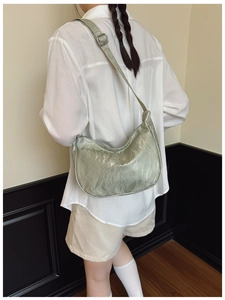 Detailed texture of light green pleated shoulder bag showing metallic sheen and strap