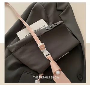 Détail de la bandoulière rose réglable avec boucle en plastique blanc sur la sangle