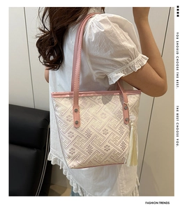Detail of floral embroidery and pink leather shoulder strap on a cream tote bag