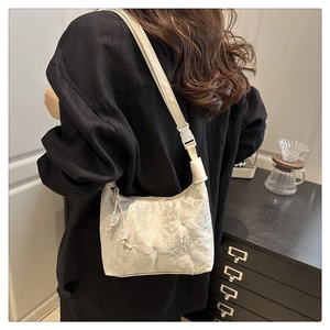 Gros plan sur le sac en dentelle beige avec papillons en relief et détails de perles