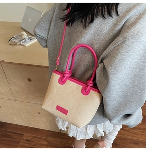 Detail of a mini woven tote bag with vibrant pink leather handles and adjustable strap