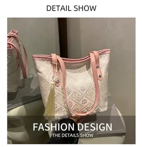 Detail of embroidered jacquard fabric tote with pink leather trim and elegant long tassel