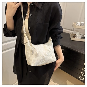 Détail d'un sac à main blanc brodé avec textures florales et pompon élégant