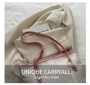 Detail of jacquard tote bag with pink leather handles and elegant tassel ornament