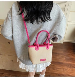 Detail of woven bucket bag with pink leather trim and adjustable crossbody strap