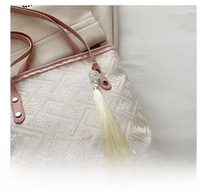 Detailed macro view of pink floral jacquard fabric and beaded tassel on the tote bag