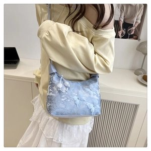 Détail d'un sac en dentelle bleu clair avec papillons 3D et cordons de serrage en perles