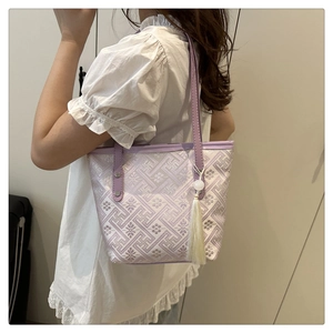 Detailed texture of lavender woven tote bag with floral patterns and white tassel charm