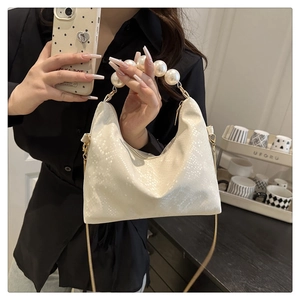 Detail showing white snake-embossed handbag with elegant pearl handle and thin shoulder strap