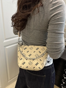 Beige bucket bag with bear print and silver chain, shown as a side view on a model