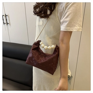 Detail of burgundy snakeskin shoulder bag with large pearl handle and gold chain