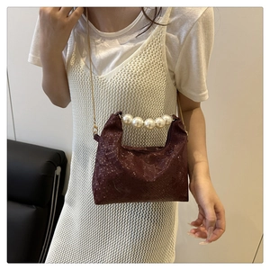 Detail of luxury burgundy snakeskin bag with pearl handle and golden chain on model