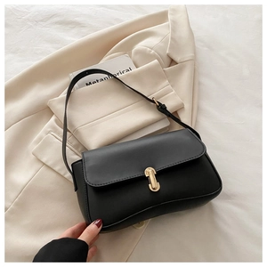 Detail of elegant gold rotary lock on black leather shoulder bag with flap design