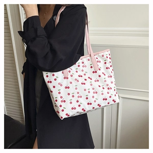 Detail of large tote bag featuring red cherry prints and pink leather shoulder straps