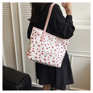 Detailed back view of a white tote bag with cherry prints and pink shoulder straps