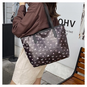 Detailed view of tote bag with floral bow print on textured dark synthetic leather