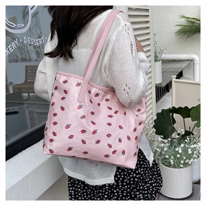 Detail shot of a pink strawberry print tote bag shown on model for size perspective