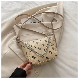 Détail du sac seau beige avec chaîne et imprimé ours posé sur une veste de costume