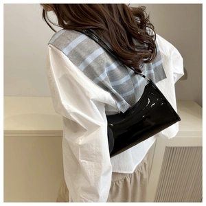 Chic black glossy leather underarm bag shown on model with minimalist style