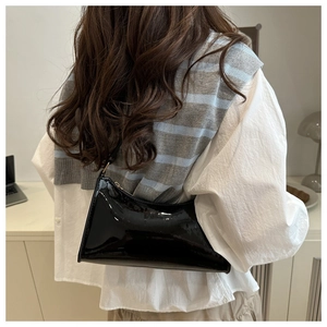 Detail of a black patent leather shoulder bag with a mirror-like finish for women