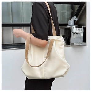 Détail d'un sac fourre-tout blanc cassé avec des bretelles kaki porté par un mannequin chic