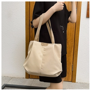 Détail du grand sac cabas beige montrant le tissu texturé et l'étiquette logo