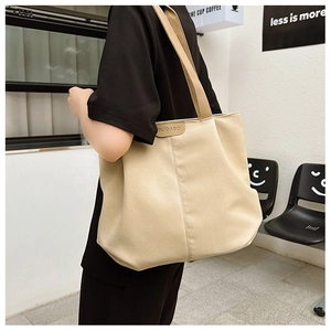 Gros plan du sac cabas en toile beige avec étiquette en cuir BUDABO et bandoulière en tissu