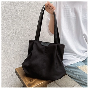Détail du sac cabas noir avec une texture plissée unique et une étiquette logo en cuir