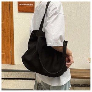 Détail d'un grand sac fourre-tout en toile noire avec larges bandoulières pour le quotidien