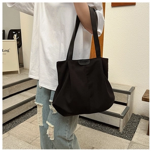 Détail du grand sac cabas noir en toile minimaliste avec étiquette logo en cuir BUDABO