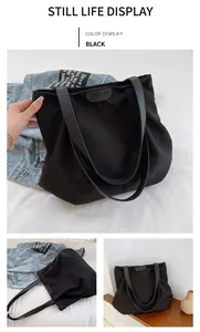 Détail d'un grand sac cabas noir avec de larges bandoulières confortables et logos
