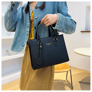 Detail of black quilted tote bag with golden lettering and a heart-shaped charm