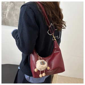 Detail view of burgundy hobo bag in polished leather with a cute plush alpaca pendant