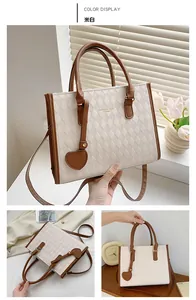 Detail of beige tote bag with rhombus texture, heart charm and brown handle straps