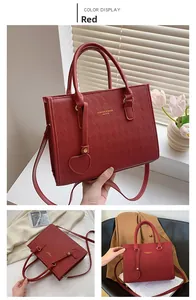 Detail of red quilted PU leather tote with heart charm and gold hardware accents