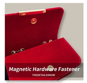 Close-up of golden magnetic snap closure on red velvet crossbody bag with luxury hardware