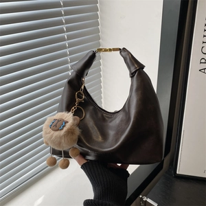 Deep brown leather crescent tote bag with gold metal lock and plush sheep charm