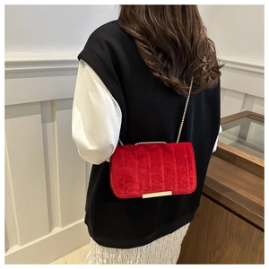 Detail of red velvet crossbody bag with vertical stitching and gold chain strap