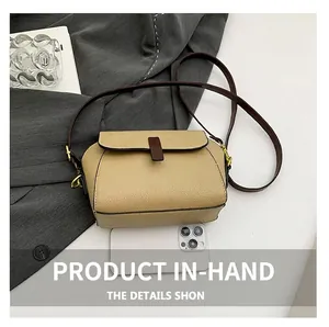 Sac bandoulière en cuir beige grainé à côté d'un smartphone pour comparer la taille