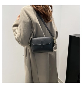 Vue latérale du sac à bandoulière en cuir noir sur un mannequin en manteau beige