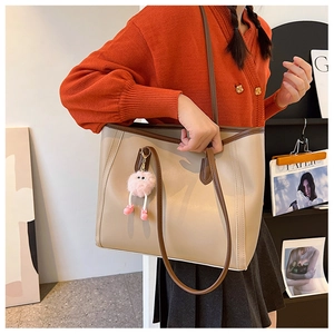 Beige large tote bag with brown handles and a cute pink monster charm accessory